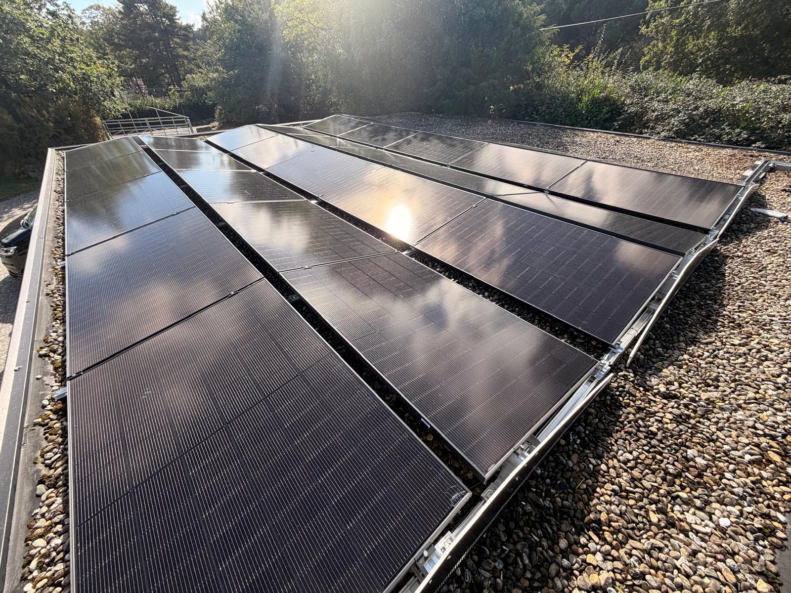 Black solar panels on a flat roof mounted on ballasted frames
