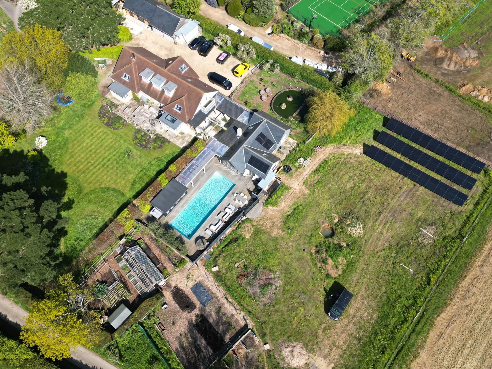 Aerial view of a home with a ground-mounted solar array